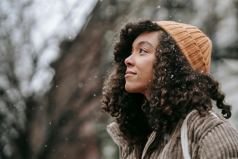 Young woman smiling, staring off into the distance, while snow gently falls